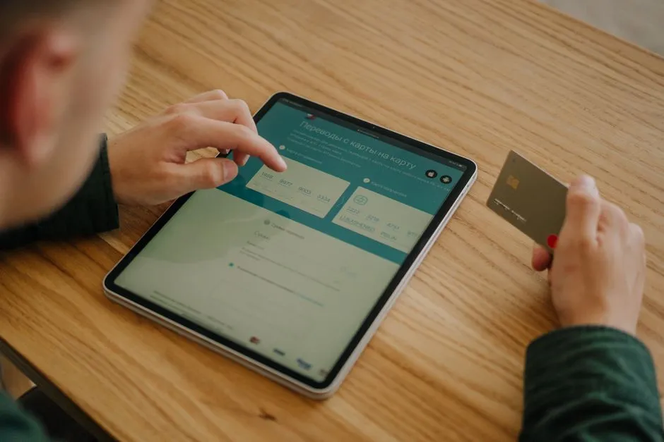 Person holding a credit card while shopping online on a tablet