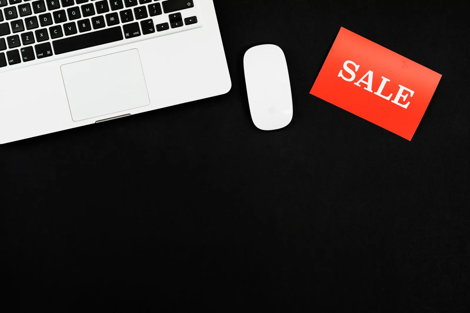 Laptop on a desk beside a red and white sale discount card